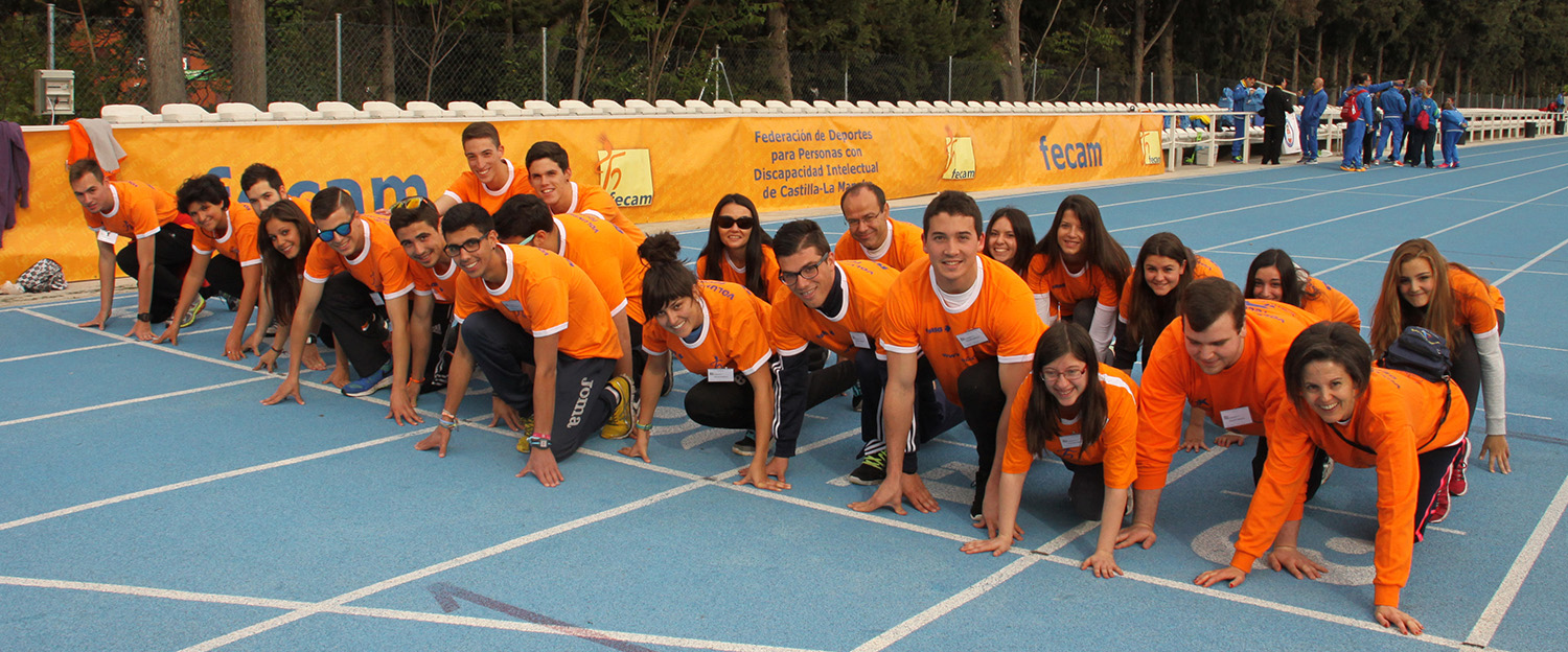 Grupo de voluntarios posando en posición de salida en pista de atletismo