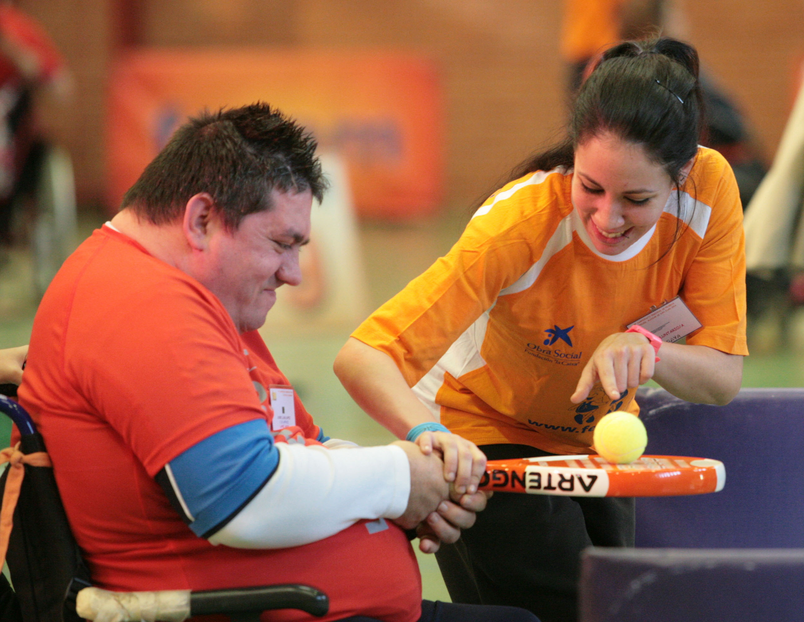 Voluntaria ayudando a deportista con pala de pádel